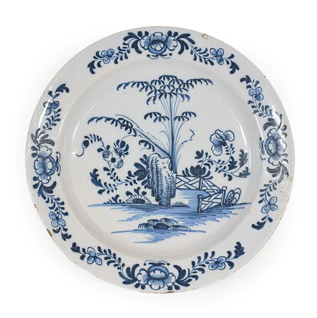 Lot 23 - An English Delft Charger, probably Liverpool, circa 1750, painted in blue with bamboo, peony...