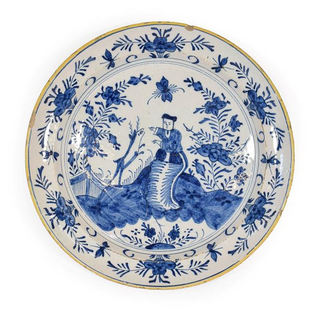 Lot 64 - A Delft Dish, circa 1750, painted in blue with a Chinese figure and a deer in a fenced garden...