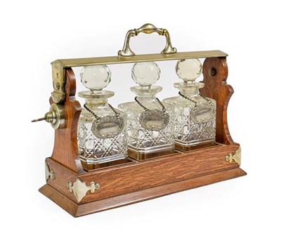 Lot 122 - A Silver Plate Mounted Oak Three-Bottle Tantalus, circa 1900, with scroll handle and...