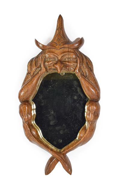 Lot 129 - A Carved Oak ''Witch Mirror'', mid 20th century, carved as a seated figure with pointed hat and...