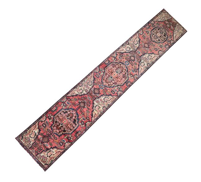 Lot 355 - Malayir Runner West Iran, circa 1930 The faded rose pink field of flowers flanking medallions...