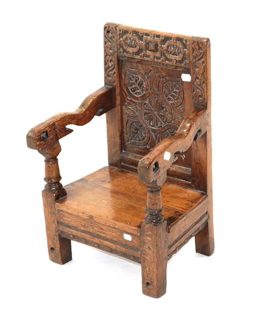 Lot 424 - ~ An English Joined Oak Child's Armchair, the strapwork carved top rail above a leaf carved...