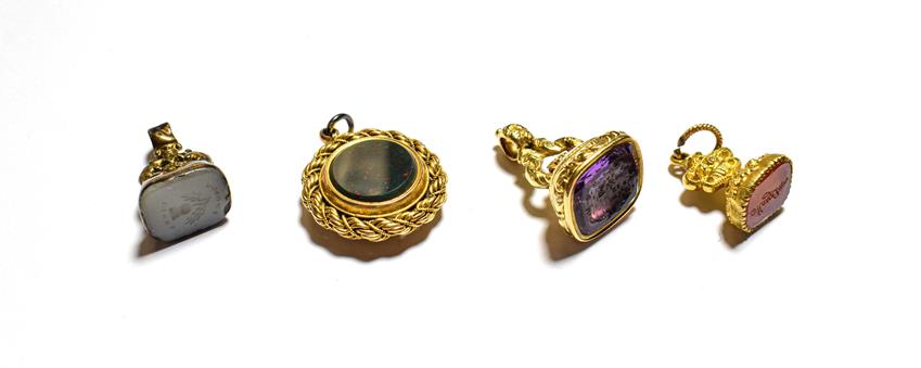Lot 90 - A gilt metal fob seal set with carnelian; a gilt metal fob seal set with purple glass, another gilt