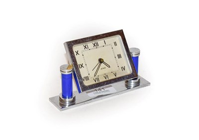 Lot 141 - An Art Deco chrome plated bedside alarm timepiece, dial signed 'Jaz', raised upon blue columns, 8cm