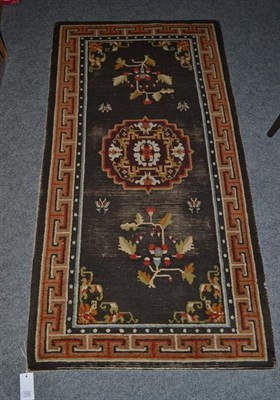 Lot 1100 - An Indian Rug, the blood red field centred by a floral medallion enclosed by meandering vine...