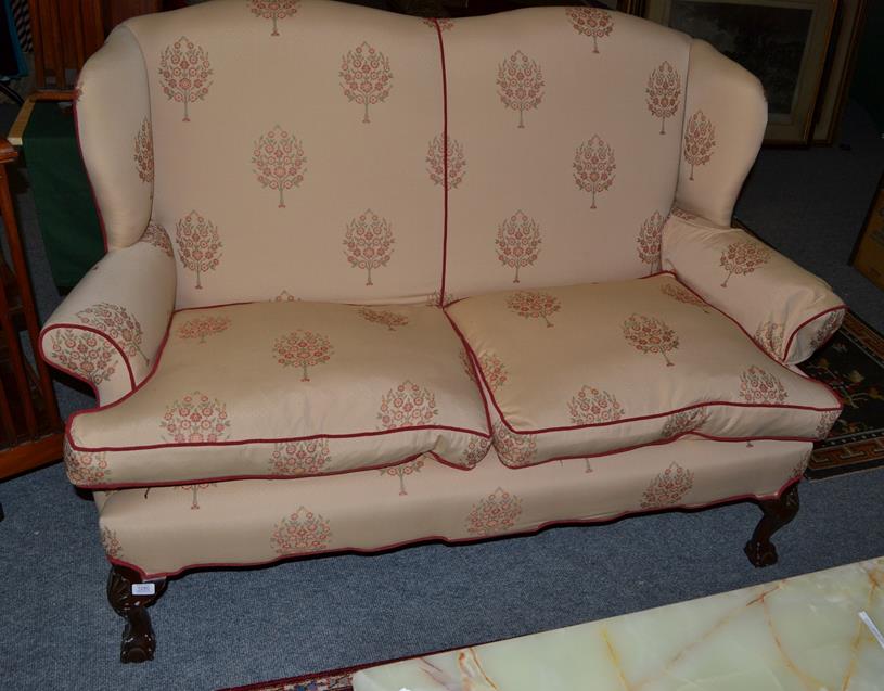 Lot 1280 - A wing back two seater sofa on ball and claw feet, 163cm