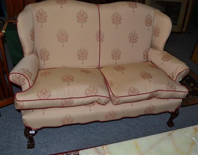 Lot 1280 - A wing back two seater sofa on ball and claw feet, 163cm