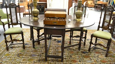 Lot 1311 - An oak gateleg table, 177cm by 130cm by 77cm, together with five high caned back chairs and one...