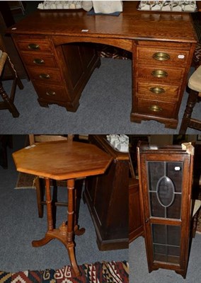 Lot 1335 - An early 20th century oak knee hole desk, 122cm by 74cm by 74cm; together with a glazed narrow...