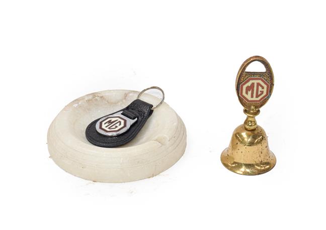 Lot 9 - An MG Circular Marble Showroom Ashtray; A Brass Novelty Tea Bell, with MG emblem; and An MG Leather