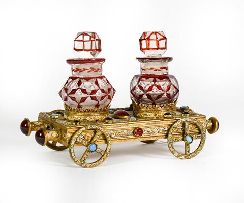 Lot 13 - A Gilt-Metal, Gem-Set and Enameled Bottle-Stand, in the form of a flatbed rail carriage, set...