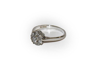 Lot 100 - An 18 carat white gold diamond cluster ring, the central raised round brilliant cut diamond...