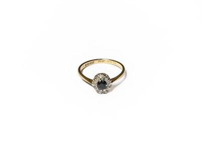 Lot 205 - An 18 carat gold sapphire and diamond cluster ring, the oval cut sapphire within a border of...