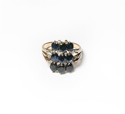 Lot 209 - A sapphire and diamond cluster ring, three rows of trios of oval cut sapphires with eight-cut...