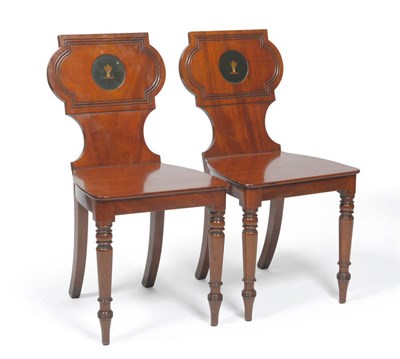 Lot 1543 - A Pair of Regency Mahogany Hall Chairs, early 19th century, each with circular green painted family