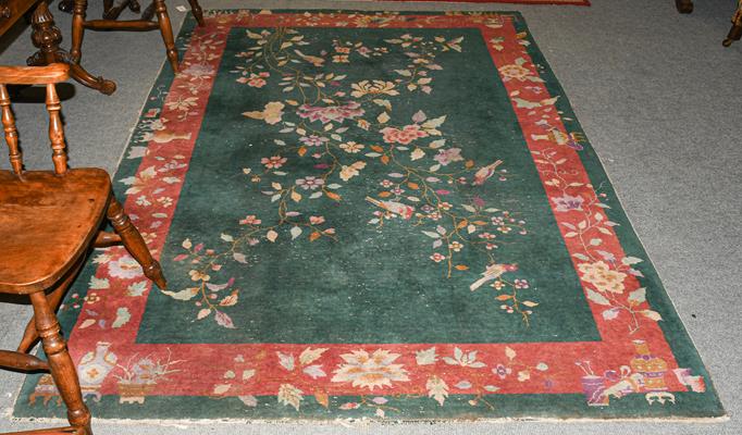 Lot 1211 - A Chinese rug, the emerald field of birds and flowering plants enclosed by floral borders, 268cm by