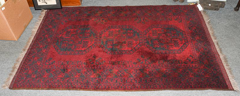 Lot 1213 - An Afghan Turkmen rug, the deep claret field with three elephant foot guls enclosed by multiple...