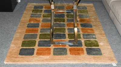 Lot 1220 - A 20th century wool rug, with green, blue and orange rectangles on an oatmeal ground, labelled...