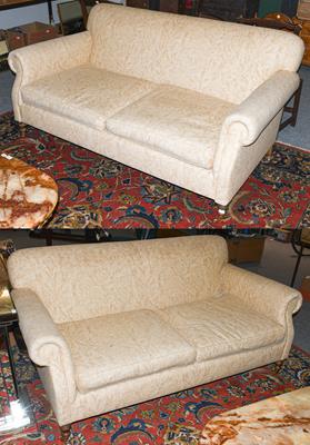 Lot 1238 - A pair of cream upholstered three seater sofas with scroll arms and moving on castors, 185cm by...