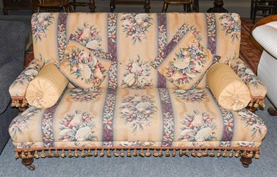Lot 1338 - A Victorian sofa raised on turned legs and brass castors, upholstered in floral and fruiting...