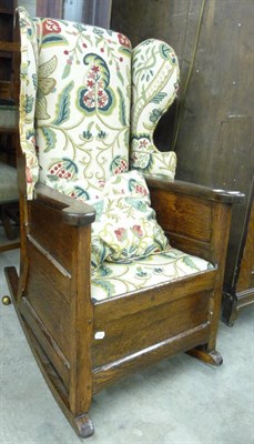 Lot 1584 - A Late 19th Century Joined Oak Wing Back Rocking Chair, upholstered in modern crewelwork...