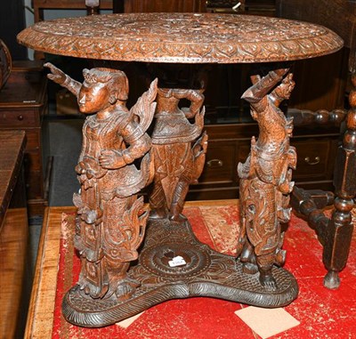 Lot 1357 - A 20th century Anglo Indian table ornately carved on three figural supports, 64cm diameter by...