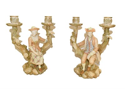 Lot 98 - A pair of Royal Worcester candelabra, modelled with figures seated on a tree stump with two sconces
