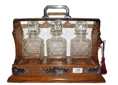 Lot 138 - An oak three bottle tantalus with silver plated mounts (with key)