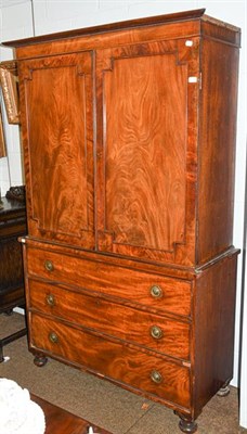 Lot 1132 - A George III figured mahogany linen press with panelled doors, and raised on a three drawer...