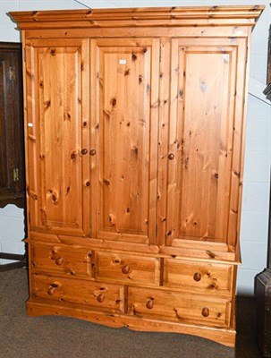 Lot 1146 - A modern pine triple wardrobe, raised on a bank of five drawers, 140cm by 56cm by 201cm