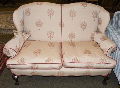 Lot 1192 - A wing back two seater sofa on ball and claw feet, 163cm wide