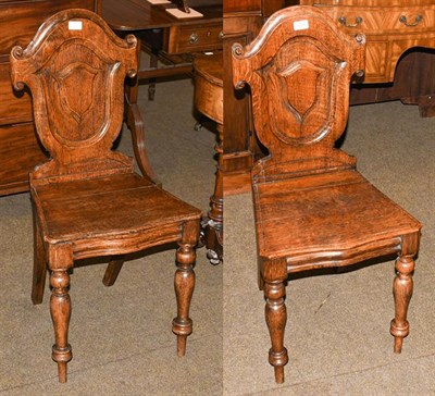 Lot 1208 - A pair of 19th century oak shield back hall chairs raised on turned supports