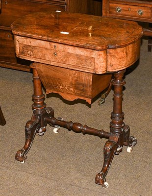 Lot 1210 - A Victorian figured walnut work table, inlaid and raised on turned supports over carved scroll feet