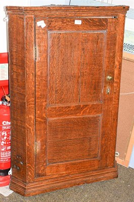 Lot 1238 - A George III oak hanging corner cupboard with panelled door, 75cm by 46cm by 110cm