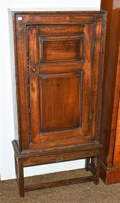 Lot 1245 - An 18th century oak single door side cabinet on stand, with panelled door, 67cm by 26cm by 137cm