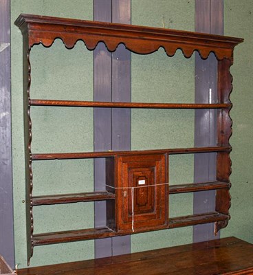 Lot 1248 - A Georgian oak wall rack with shaped pediment and single cupboard inlaid with shell patera,...