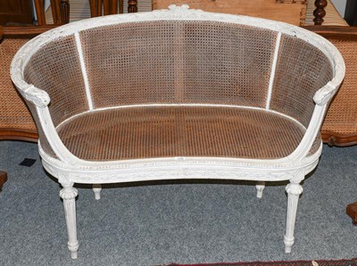 Lot 1290 - A French carved and painted bergere parlour settee of tub form, raised on reeded tapering supports