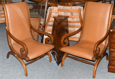 Lot 1300 - A pair of 20th century armchairs with mahogany scrolling arms, covered in tan leather