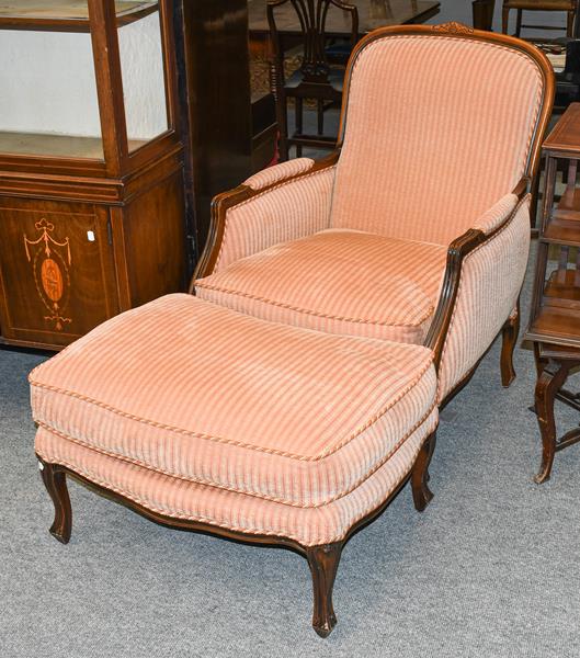 Lot 1313 - A modern French style carved walnut upholstered armchair and footstool, raised on scroll...