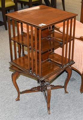 Lot 1314 - An Edwardian crossbanded mahogany rotating bookcase, raised on scroll supports, with X frame...