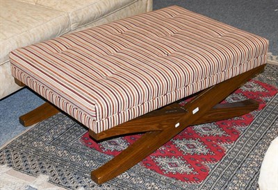 Lot 1322 - A large modern footstool with deep buttoned striped upholstery, raised on an X frame hardwood base