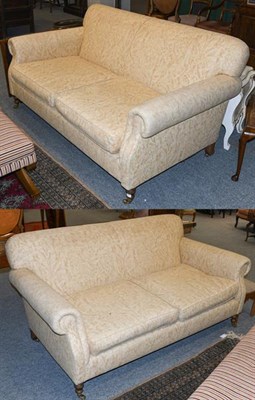 Lot 1323 - A pair of cream upholstered three seater sofas, with scroll arms and moving on castors, 185cm...