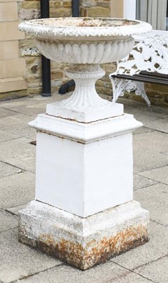 Lot 1343 - A white cast iron garden urn of fluted pedestal form, raised on a stepped rectangular plinth, 127cm