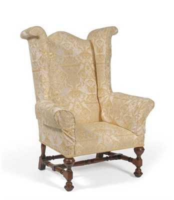 Lot 1696 - A 17th Century Style Walnut Wing Back Chair, probably 19th century, upholstered in cream gold fleur