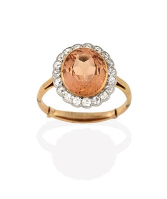Lot 2219 - A Topaz and Diamond Cluster Ring, the oval cut topaz in a yellow rubbed over setting, within a...