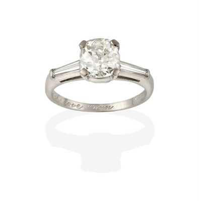 Lot 2248 - A Diamond Solitaire Ring, the cushion cut diamond in a white four claw setting, to tapered baguette
