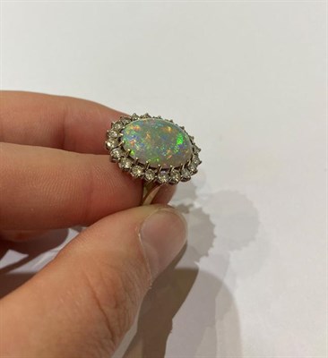Lot 2249 - An 18 Carat White Gold Opal and Diamond Cluster Ring, the oval cabochon opal within a border of...