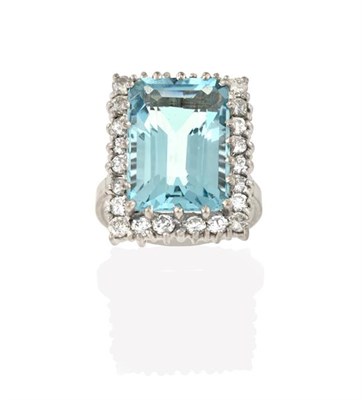 Lot 2251 - An Aquamarine and Diamond Cluster Ring, the emerald-cut aquamarine within a border of round...
