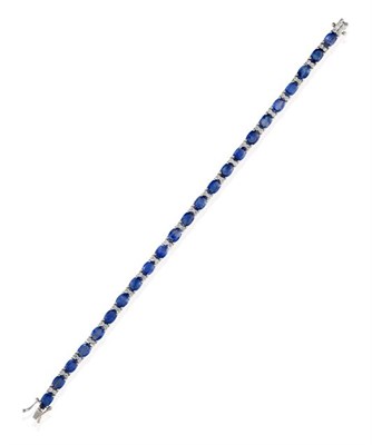 Lot 2283 - A Sapphire and Diamond Bracelet, twenty-three oval cut sapphires alternate with pairs of round...