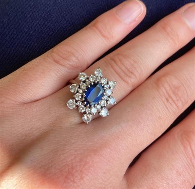 Lot 2284 - A Sapphire and Diamond Cluster Ring, the oval cut sapphire within a double border of round...